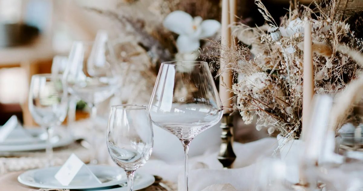 Feestelijk gedekte trouwtafel met droogbloemen, kaarsen en kaartjes bij de borden